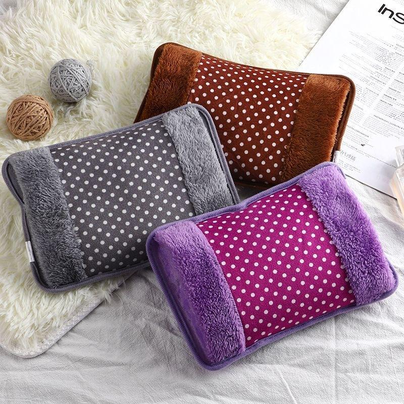 Three polka dot heating pads in gray, brown, and purple on a textured surface.