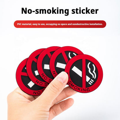 Hand holding a no-smoking sticker with red border and black center on a white background