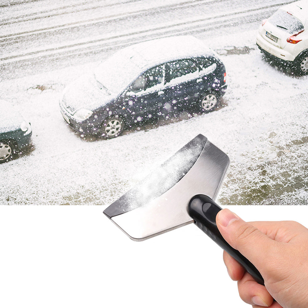 Person using a snow scraper on a car window with snow-covered ground and cars in the background.